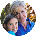 Grandmother and granddaughter smiling outside.