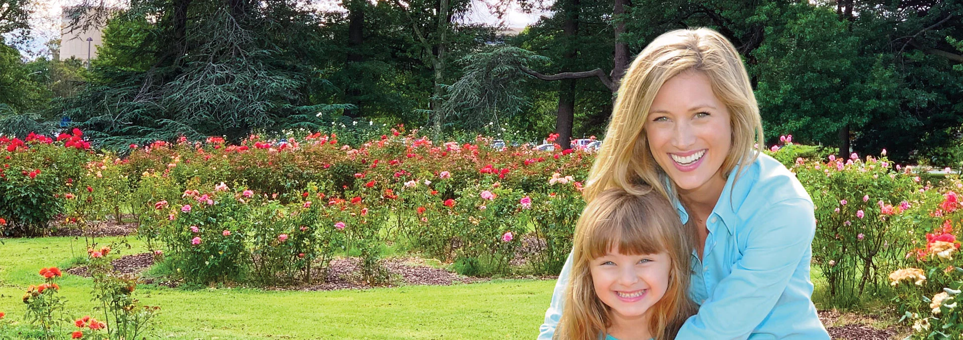 Mother and daughter smiling in a graden of flowers.